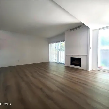 an empty room with wooden floor fireplace and windows