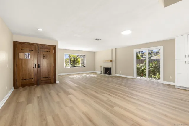 a view of an empty room with a window and wooden floor