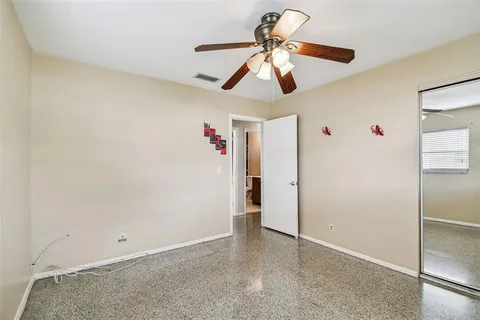 an empty room with a chandelier fan and wooden floor