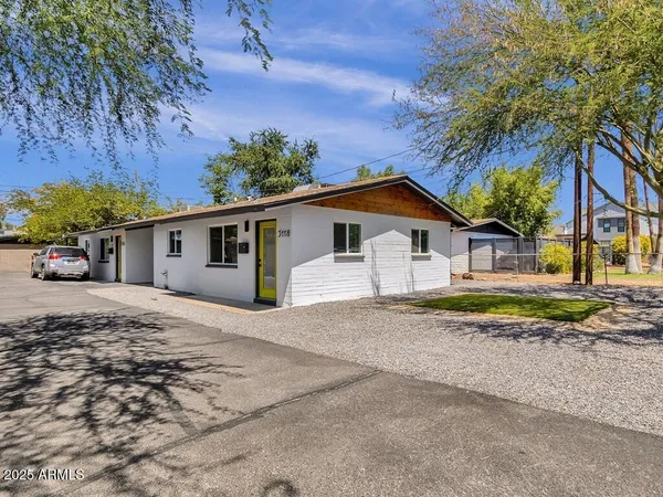 a view of a house with a yard and large trees