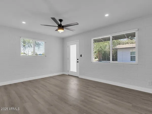 a view of an empty room with wooden floor and a window