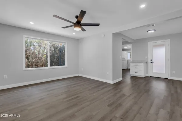 a view of an empty room with a window and wooden floor