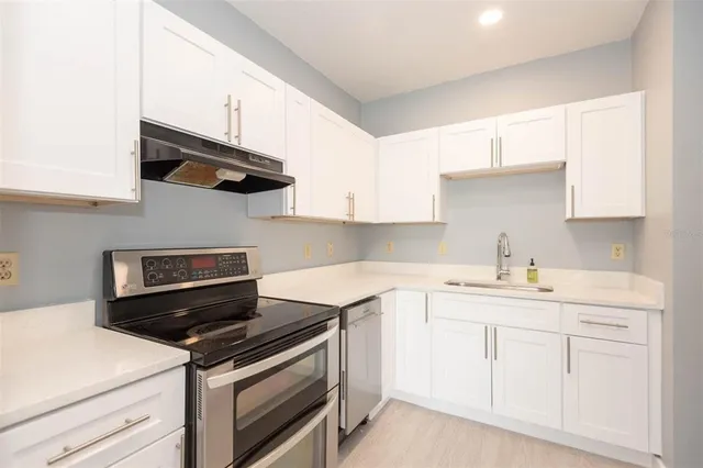 a kitchen with white cabinets and appliances