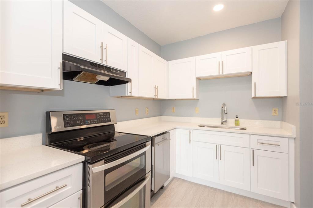 946 15th Street, Unit 202 Daytona Beach, FL 32117 - Photo 21 of 40 a kitchen with white cabinets and appliances