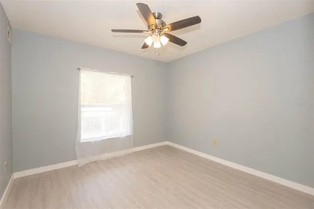 an empty room with a window and a fan