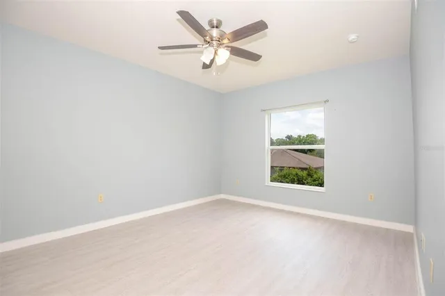 an empty room with windows and ceiling fan