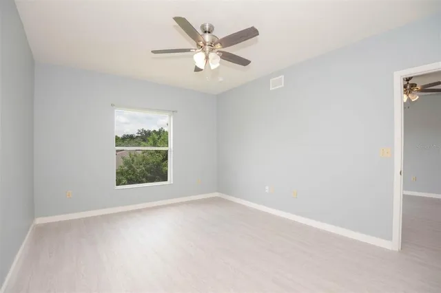 an empty room with a window and a ceiling fan