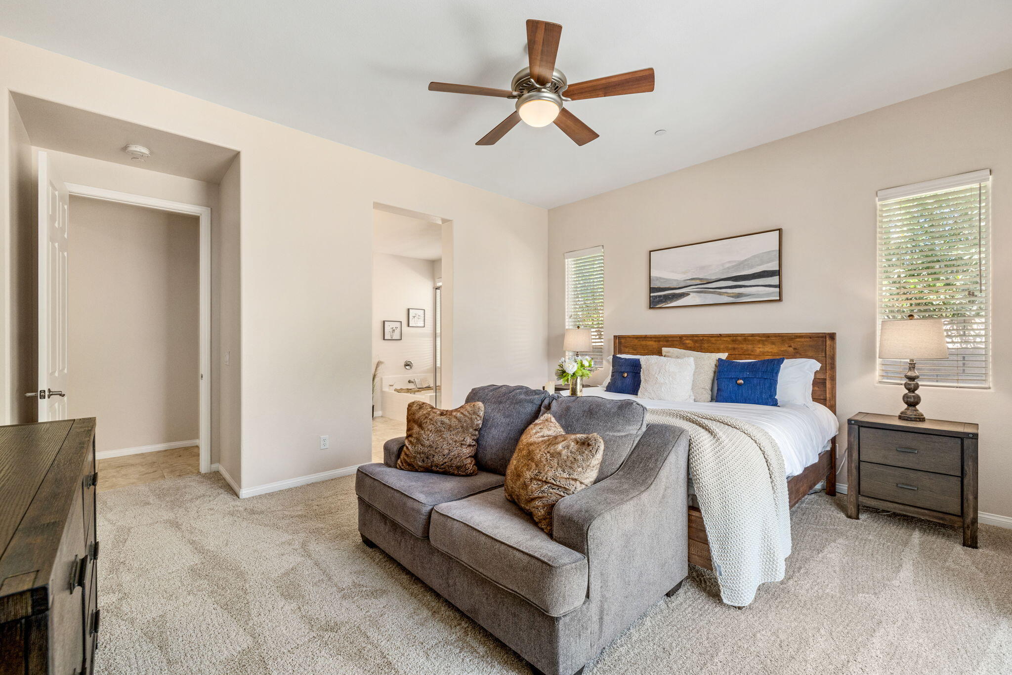 41252 Gaslight Avenue Bermuda Dunes, CA 92203 - Photo 14 of 37 a spacious bedroom with a bed a couch and a ceiling fan