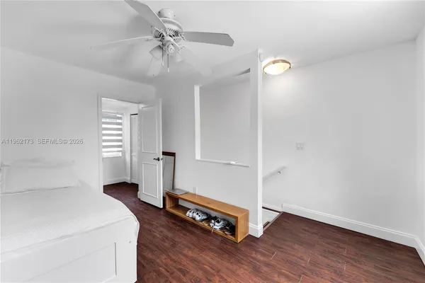 a view of an empty room with window wooden floor and a ceiling fan