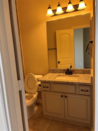 a bathroom with a granite countertop bathtub shower sink vanity and toilet