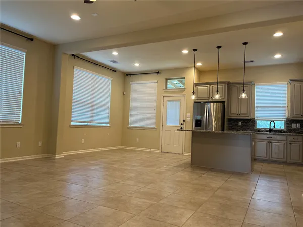 a view of kitchen with stainless steel appliances kitchen island granite countertop cabinets and window