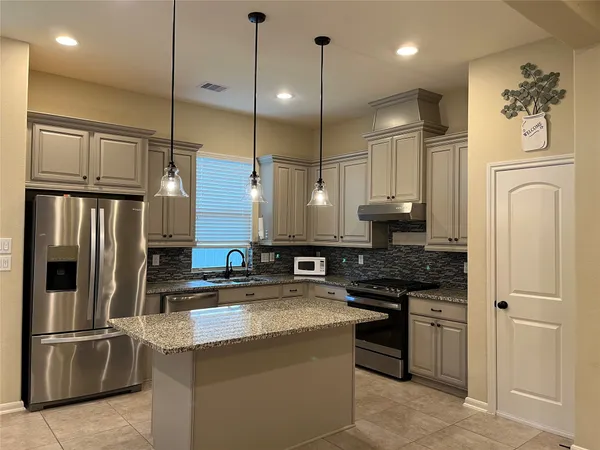 a kitchen with stainless steel appliances granite countertop a refrigerator a oven and a sink with wooden floor