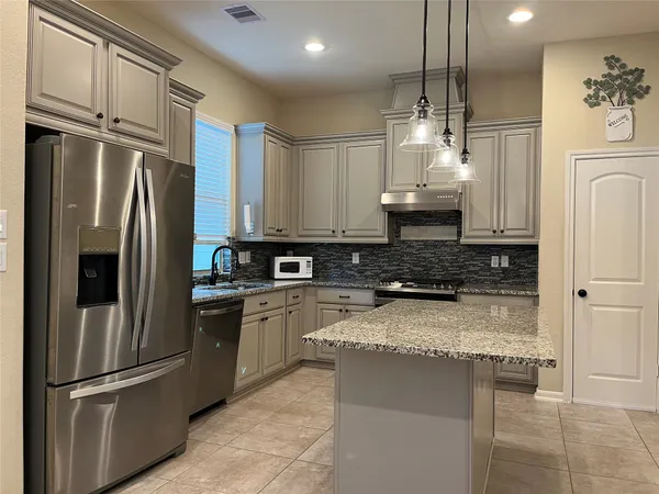 a kitchen with stainless steel appliances granite countertop a refrigerator a stove and a sink