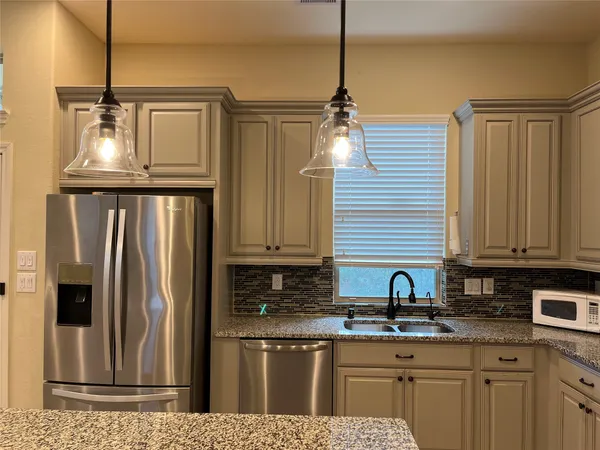 a kitchen with stainless steel appliances granite countertop a refrigerator a sink and wooden cabinets