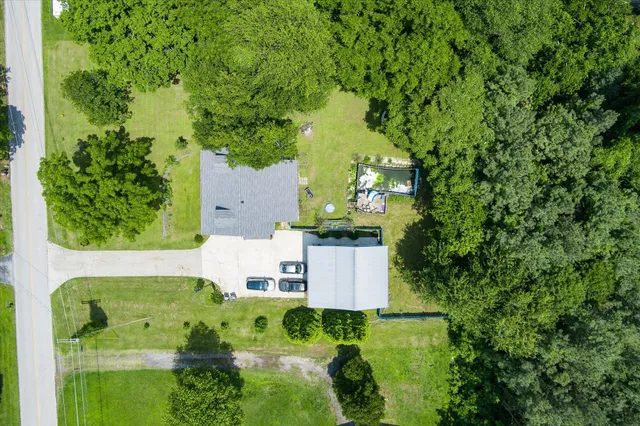 an aerial view of residential house with outdoor space and trees all around