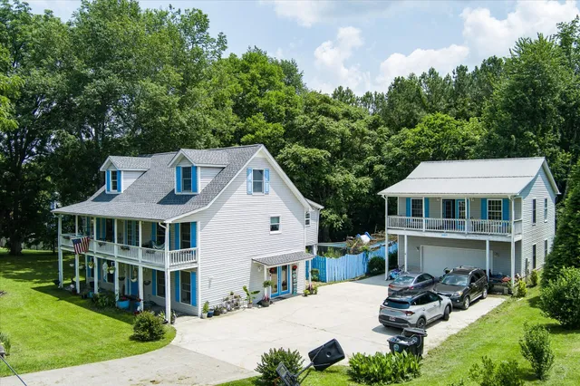 a view of a white house with a yard table and chairs