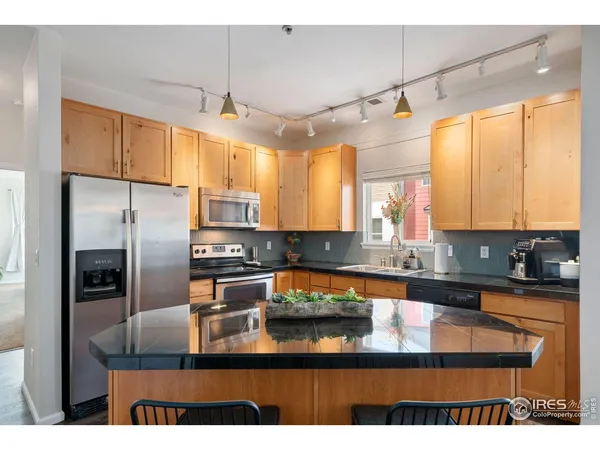 a kitchen with stainless steel appliances granite countertop a sink a stove and refrigerator