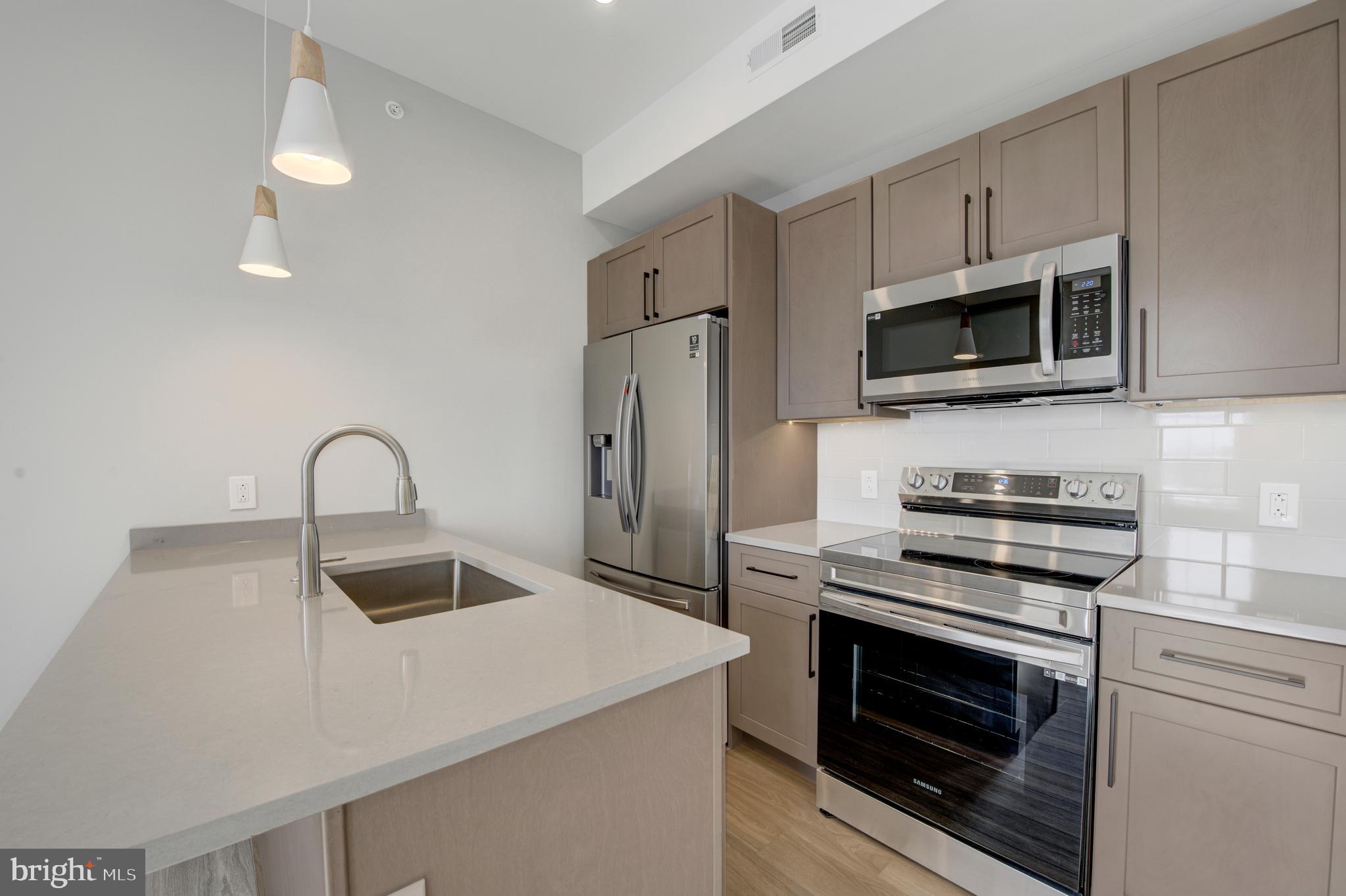 2445 Innovator Way, Unit 4G Philadelphia, PA 19146 - Photo 4 of 32 a kitchen with stainless steel appliances a stove microwave and sink