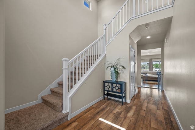 955 Delorean Lane Midvale, UT 84047 - Photo 5 of 47 Two-story entryway with a carpeted staircase featuring a white railing, wood-finish flooring, and a second-story transom window