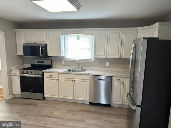 a kitchen with granite countertop a refrigerator stove and sink