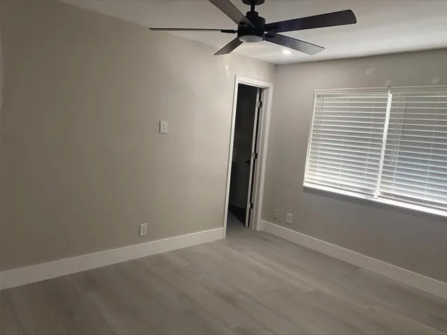 an empty room with a window and a fan