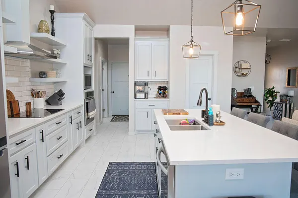 a kitchen with stainless steel appliances a sink a stove a refrigerator and white cabinets