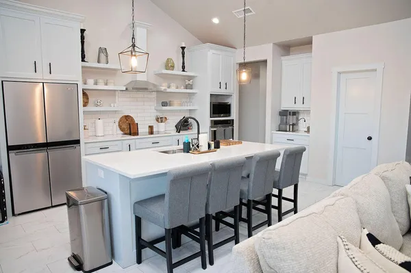 a kitchen with stainless steel appliances a dining table chairs refrigerator and sink