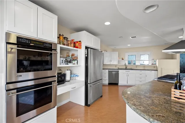 a kitchen with stainless steel appliances granite countertop a refrigerator a stove and a sink