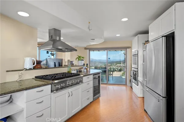 a kitchen with stainless steel appliances granite countertop a refrigerator a stove and a sink