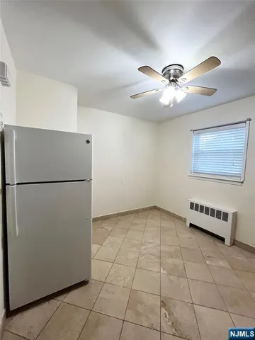 a view of a refrigerator in kitchen and an empty room