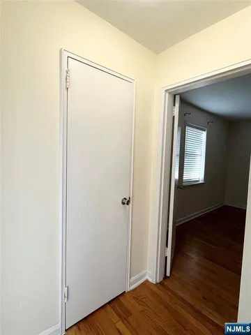 a view of an empty room with wooden floor and closet