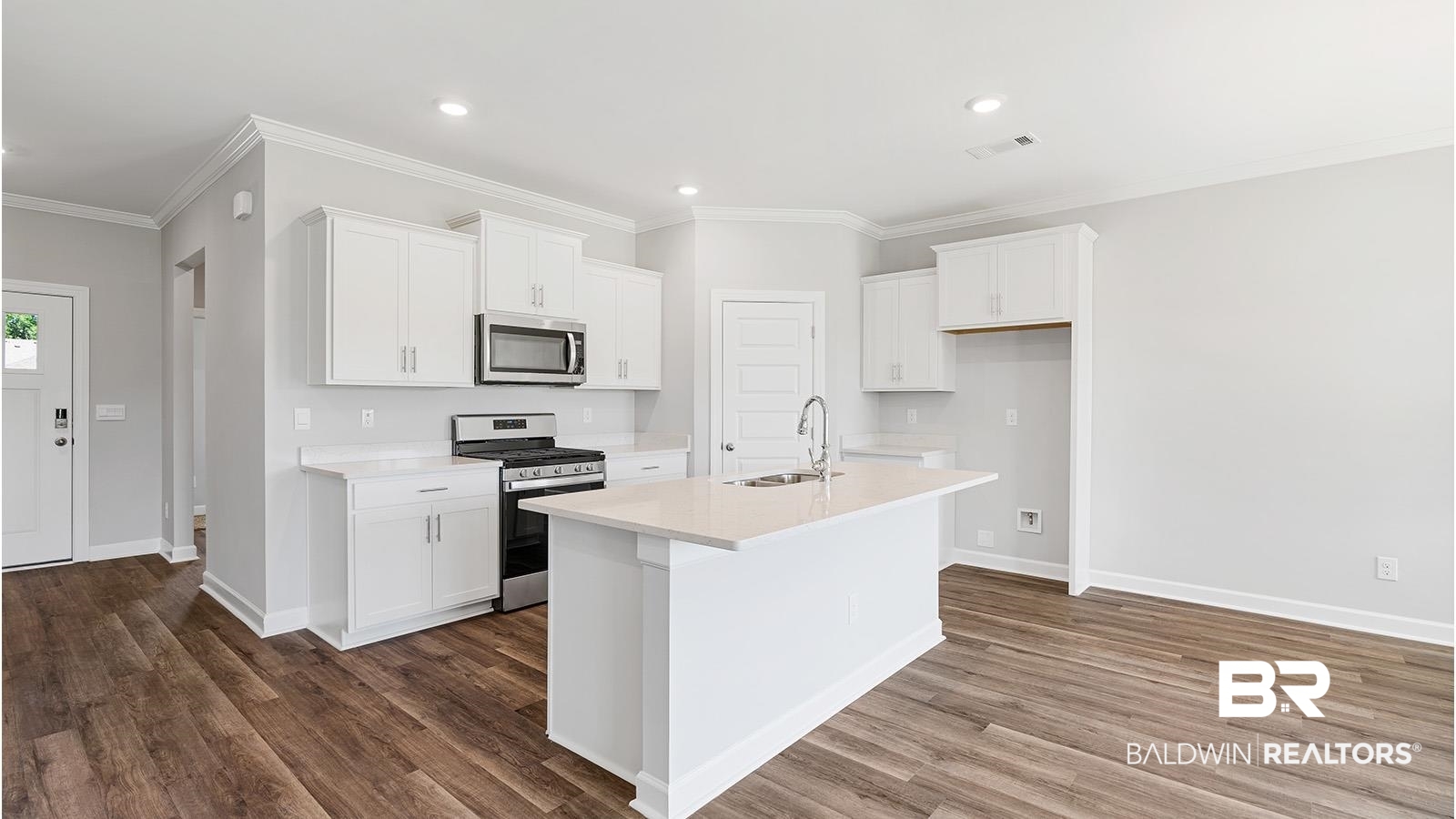 30567 Asheville Road Daphne, AL 36527 - Photo 3 of 29 Kitchen with ornamental molding, appliances with stainless steel finishes, white cabinetry, a center island with sink, and dark wood-style flooring