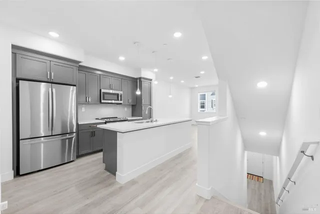 a kitchen with stainless steel appliances granite countertop a refrigerator and a stove top oven