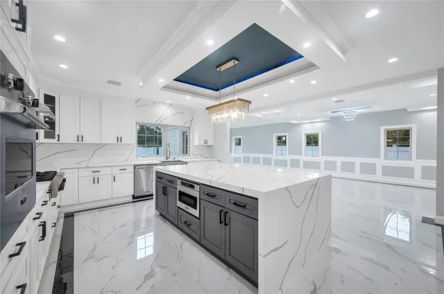 a large kitchen with stainless steel appliances granite countertop a large kitchen island a stove a sink a refrigerator and a cabinets