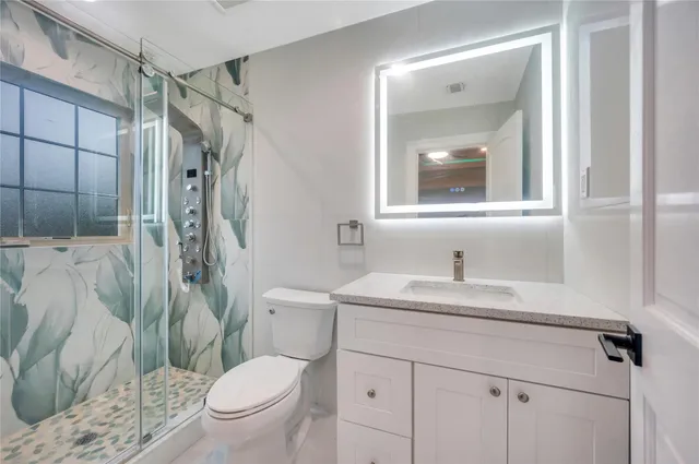 a bathroom with a sink toilet vanity and shower