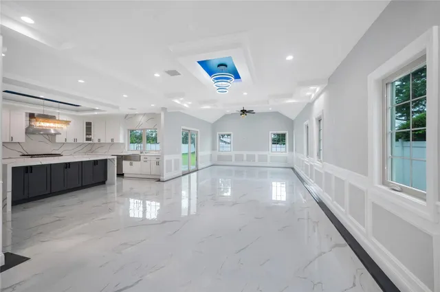 a view of an empty room and kitchen with furniture and a window