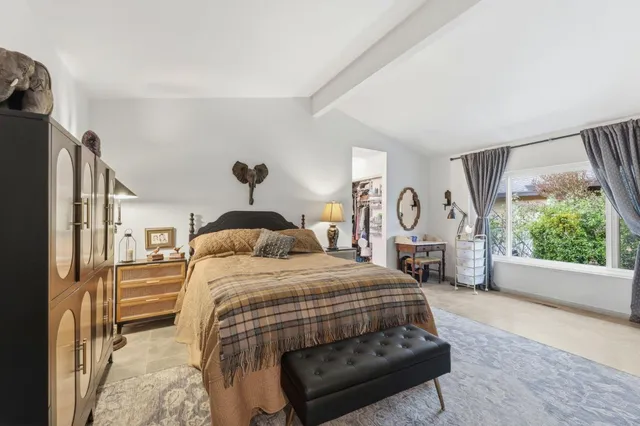 a bedroom with a bed a mirror on dresser and a large window
