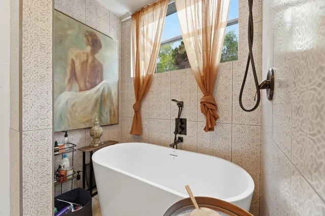 a bathroom with a white tub a window and a shower