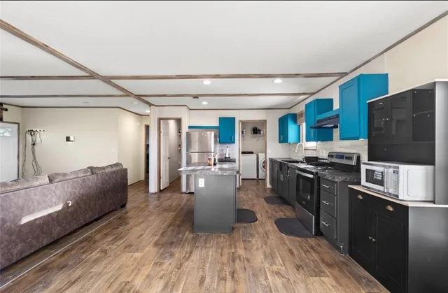 a living room with stainless steel appliances furniture and a kitchen view