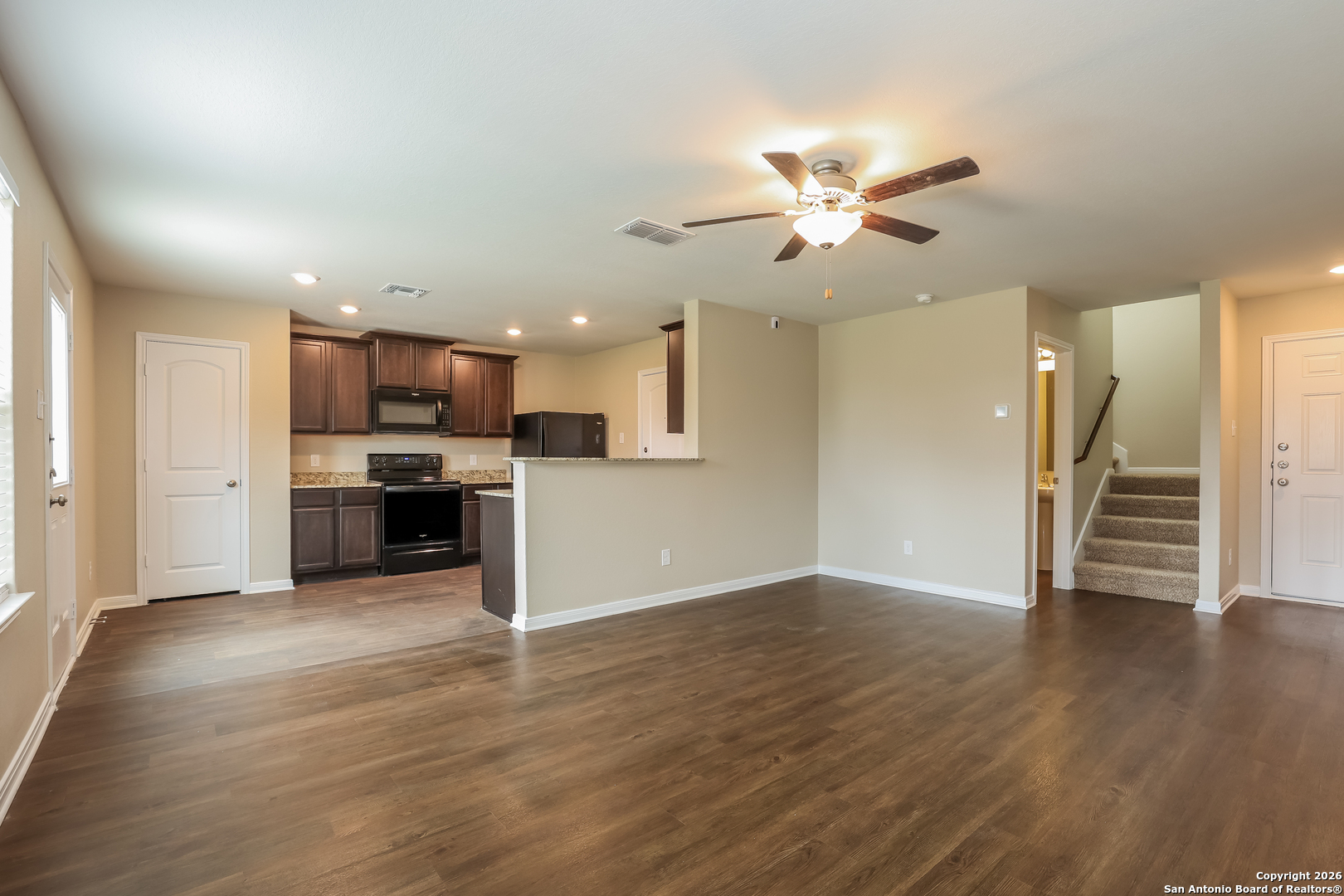 7213 Romaire San Antonio, TX 78252 - Photo 7 of 15 a view of a kitchen with a stove cabinets wooden floor and a ceiling fan