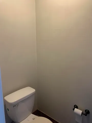 a white toilet sitting next to a white wall