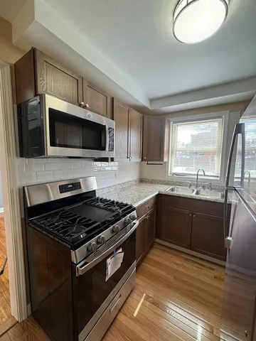 a kitchen with granite countertop a stove top oven a sink dishwasher a microwave oven with cabinets and wooden floor