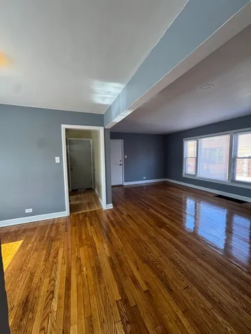 a view of empty room with window and wooden floor