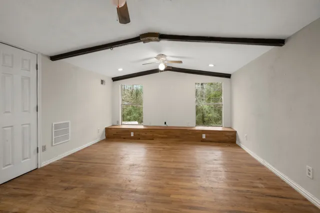 a view of an empty room with wooden floor and a window
