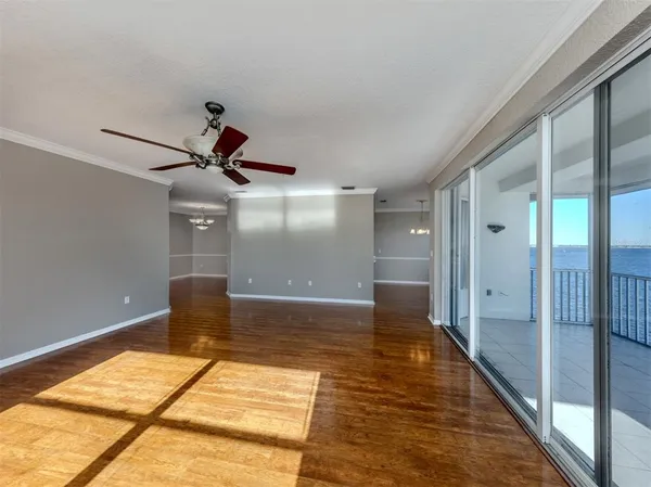 a view of empty room with wooden floor and fan