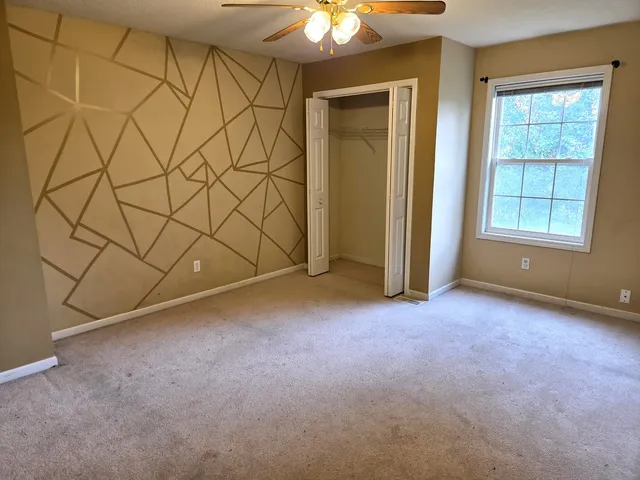an empty room with windows and ceiling fan