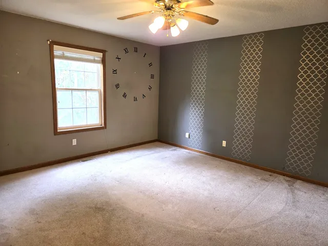 an empty room with windows and chandelier fan