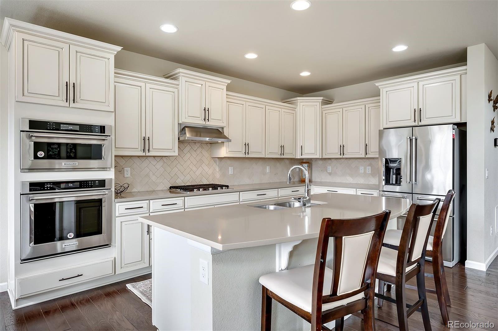 a kitchen with stainless steel appliances granite countertop a stove a refrigerator a microwave and white cabinets