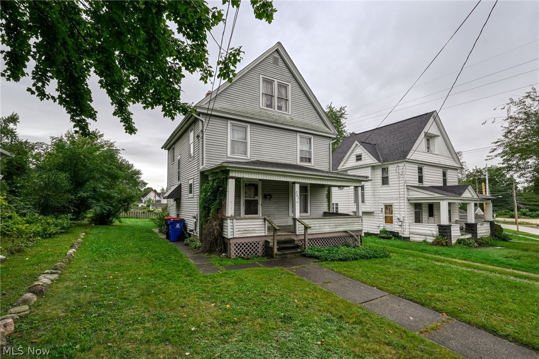 267 West Riddle Avenue Ravenna, OH 44266 - Photo 27 of 47 Classic Colonial architecture featuring a gabled roofline with multiple peaks, expansive front porch with decorative railings and stepped entry, horizontal wood siding exterior, and multi-pane windows