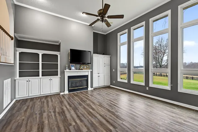 a view of a livingroom with a fireplace a ceiling fan and wooden floor